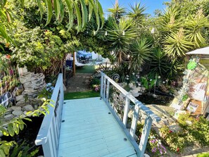 A garden pathway with a wooden deck, surrounded by various plants and a small pond. - KOI PONDS RETREAT 3K SqFt VILLA Outdoor Kitchen~Living 2B1Ba MASTER SUITE+CASITA (Fullerton)