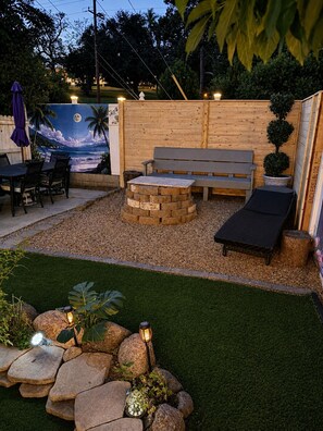 Een terras met een houten bank, een kleine ronde tafel en een eethoek.