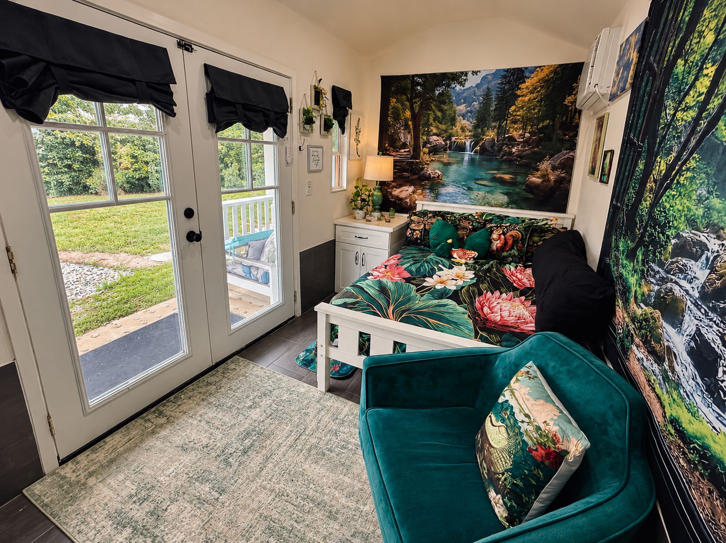 Quarto com cama, mesa de cabeceira, luminária, janela com cortinas e um quadro de uma cascata.