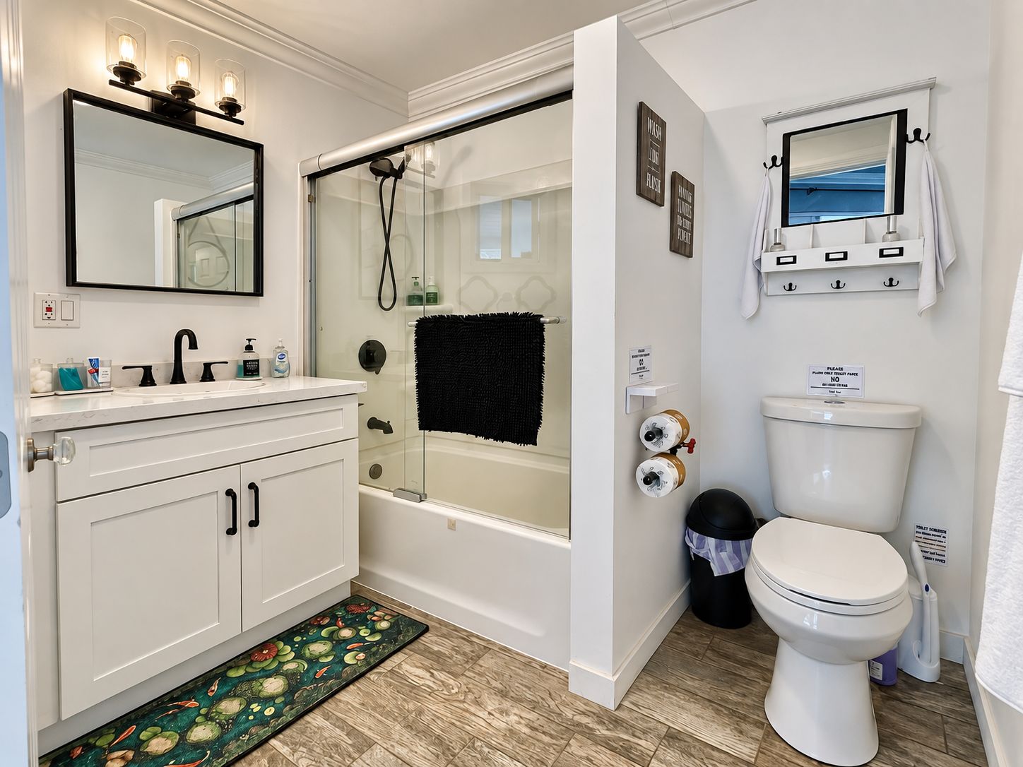 Un baño moderno con ducha envuelta en vidrio, inodoro blanco y tocador con espejo e iluminación.