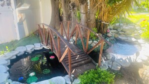A wooden bridge over a pond with lily pads and a small waterfall. - KOI PONDS RETREAT 3K SqFt VILLA Outdoor Kitchen~Living 2B1Ba MASTER SUITE+CASITA (Fullerton)