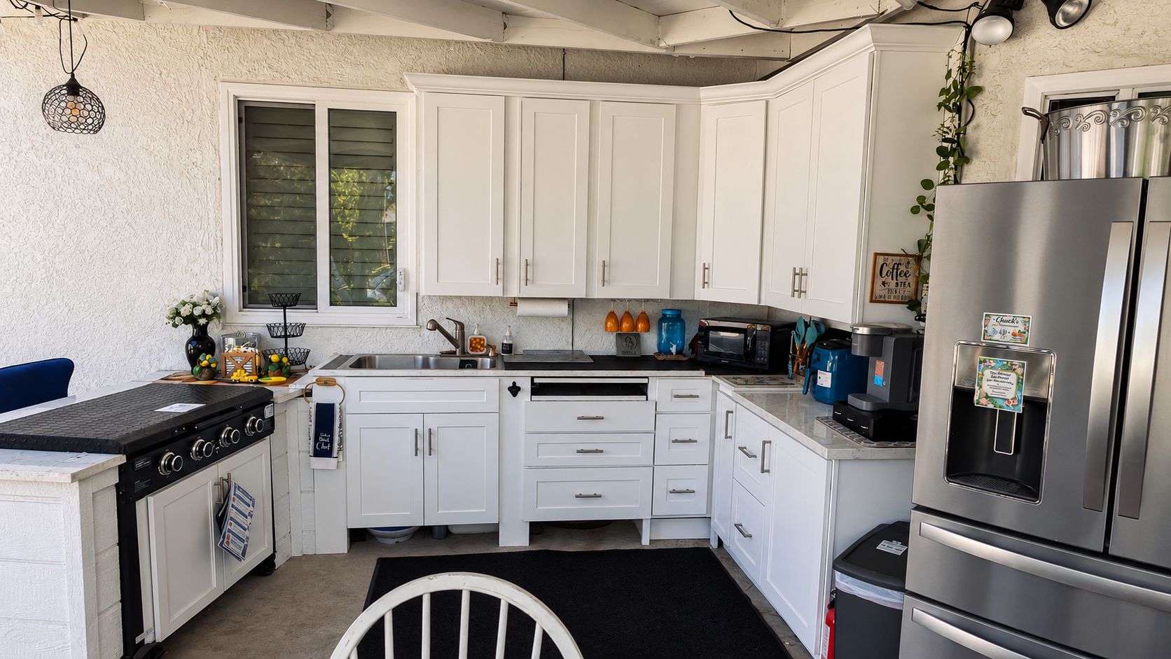 A compact kitchen with white cabinets, a stainless steel refrigerator, a stove, and a microwave.