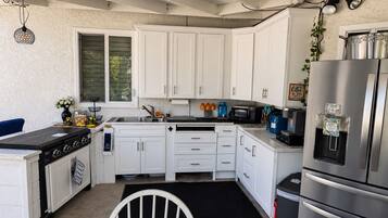 A compact kitchen with white cabinets, a stainless steel refrigerator, a stove, and a microwave.