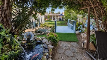A garden with a water feature, a wooden bridge, and a patio area.