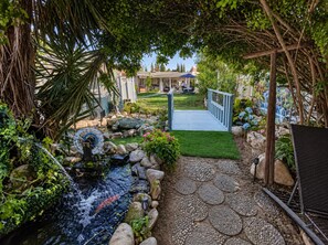 Un jardin agrémenté d’un élément aquatique, d’un pont en bois et d’un espace patio.