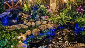 A garden with a pond, rocks, and a large crocodile model.