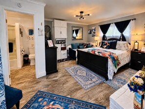 Une chambre à coucher avec un lit, des tables de chevet, une commode, un miroir et une fenêtre avec des rideaux.