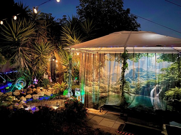 A glass-enclosed tropical garden with a waterfall, rocks, and plants.