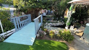 A garden with a wooden deck, a small pond, and various plants. - KOI PONDS RETREAT 3K SqFt VILLA Outdoor Kitchen~Living 2B1Ba MASTER SUITE+CASITA (Fullerton)