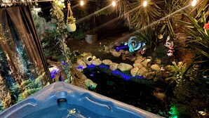 A hot tub surrounded by a garden with rocks, plants, and decorative lighting. - THE KOI PONDS RETREAT 3k Sqft OUTDOORS + Kitchen, 2Bd 1 Ba Mstr Suite & Casita (Fullerton)