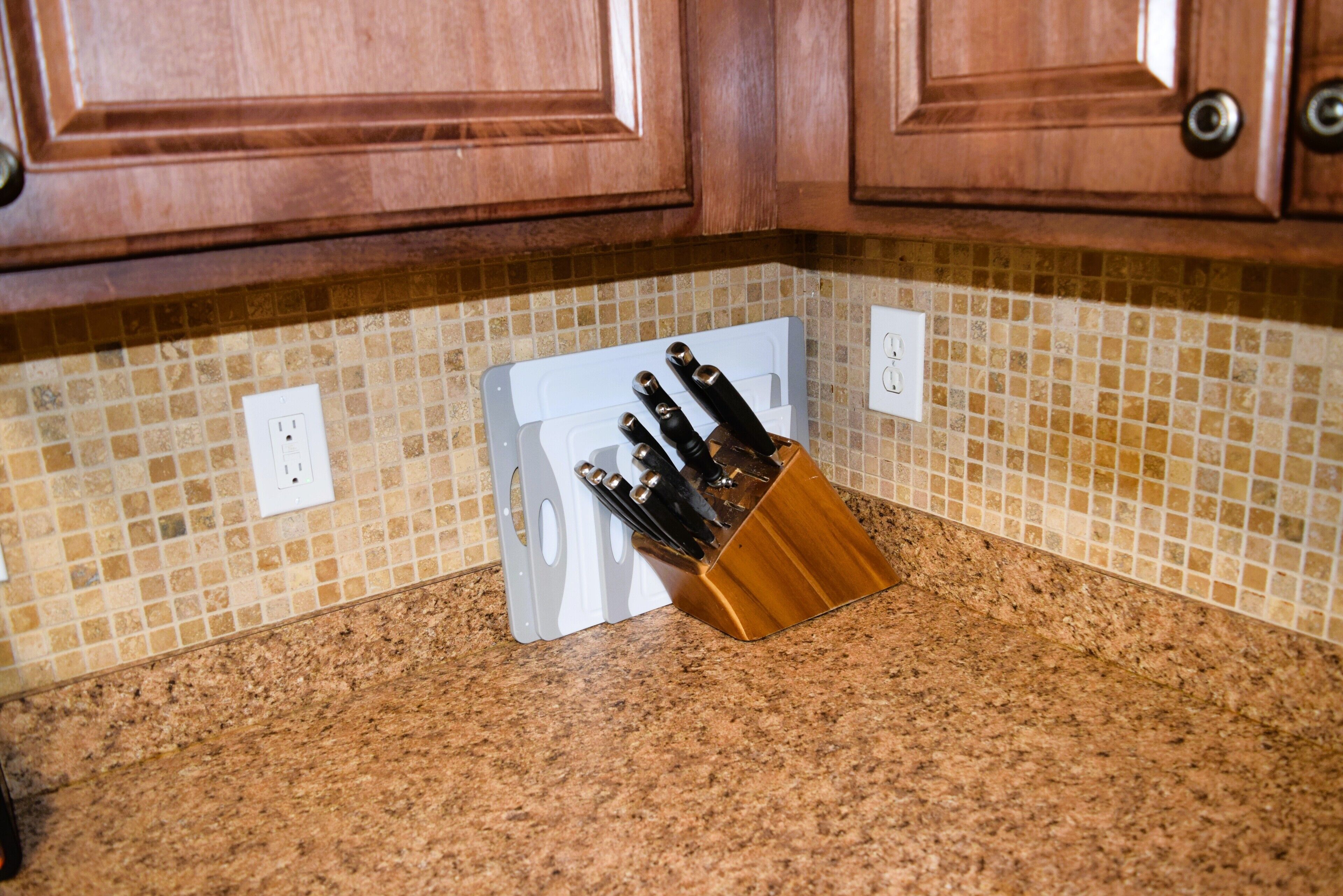 Un plan de travail de cuisine avec un range-couteaux et un pare-feu en carreaux.