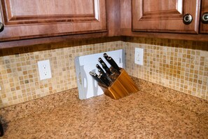 Una encimera de cocina con un bloque de cuchillos y un salpicadero de azulejos.