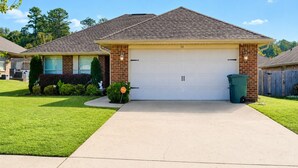 A residential house with a garage, a well-maintained lawn, and a trash bin.