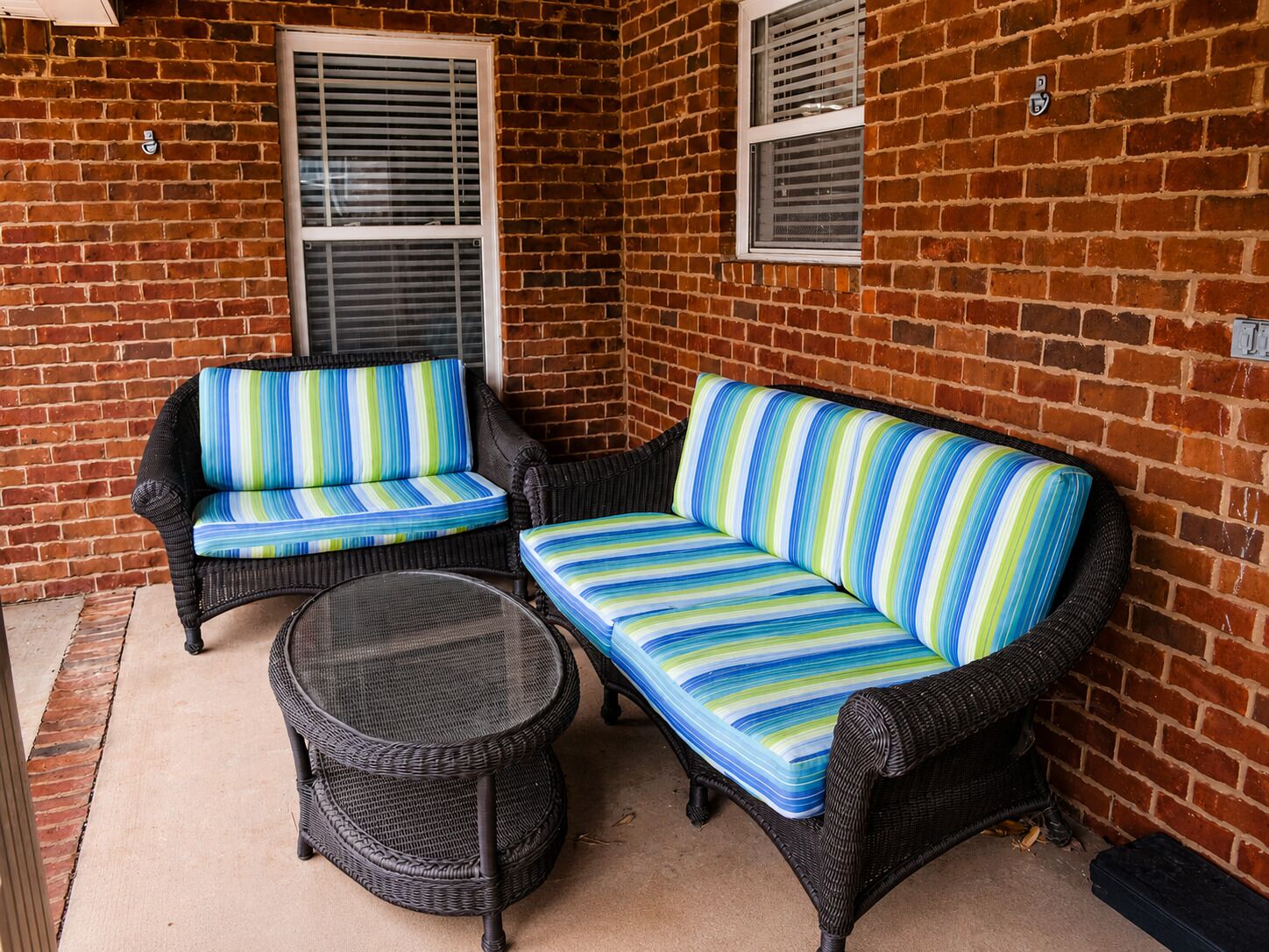 A brick patio with two wicker sofas and a round table.