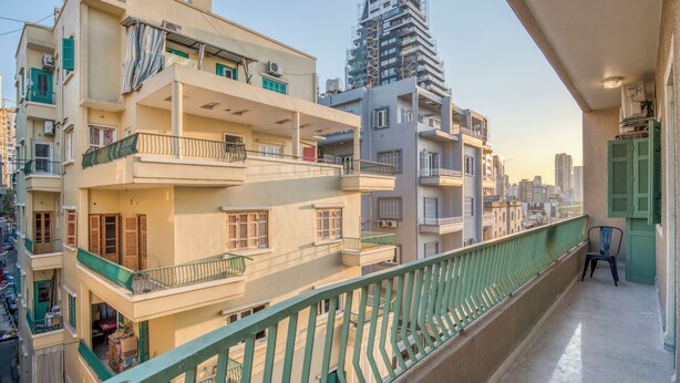 A multi-story residential building with balconies, a view of the cityscape, and a construction site in the background. - Muse 2-BR Apt in Mar Mikhael (Beirut)