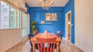 A dining area with a blue wall, a chandelier, and a table with chairs. - Muse 2-BR Apt in Mar Mikhael (Beirut)