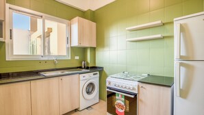 A kitchen with green walls, a washing machine, an oven, and a refrigerator. - Muse 2-BR Apt in Mar Mikhael (Beirut)