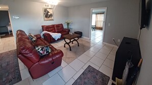 Un salon avec un canapé en cuir marron, une table basse et un téléviseur à écran plat.