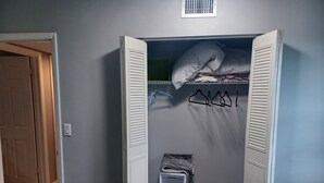 Un dressing avec des portes ouvertes, des étagères et un espace pour suspendre les vêtements.