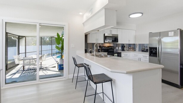 Een moderne keuken met een groot kookeiland, roestvrijstalen apparatuur en een schuifdeur naar een patio.