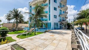 A modern building with a pool, surrounded by palm trees and a well-maintained lawn. - Apart With 2 Bedrooms, 150m From the Beach Kvd0201 (Caucaia)