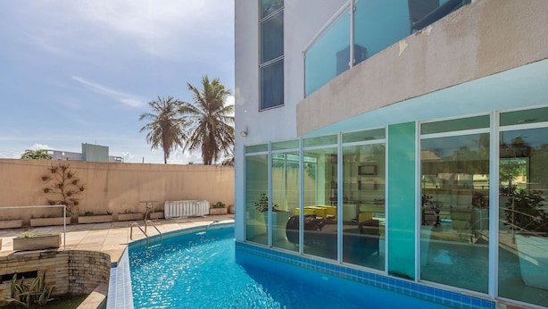 A modern building with a swimming pool, large windows, and a view of palm trees. - Apart With 2 Bedrooms, 150m From the Beach Kvd0201 (Caucaia)