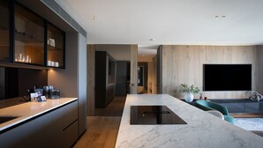 A modern kitchen with a marble countertop, built-in appliances, and a wooden accent wall. - Sky Penthouse, Tamarama (Tamarama)