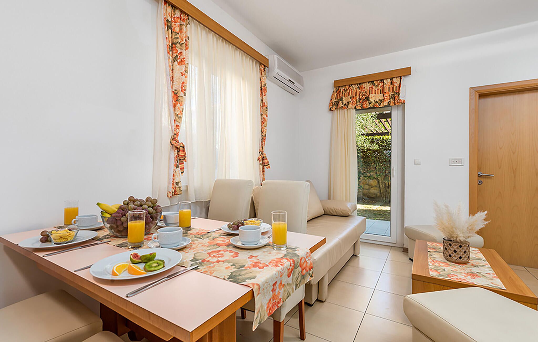 Un coin repas avec une table mise pour le petit-déjeuner, comprenant des fruits et du jus, et un canapé en arrière-plan.