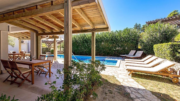 Zona exterior coberta amb piscina, gandules i taula de menjador.