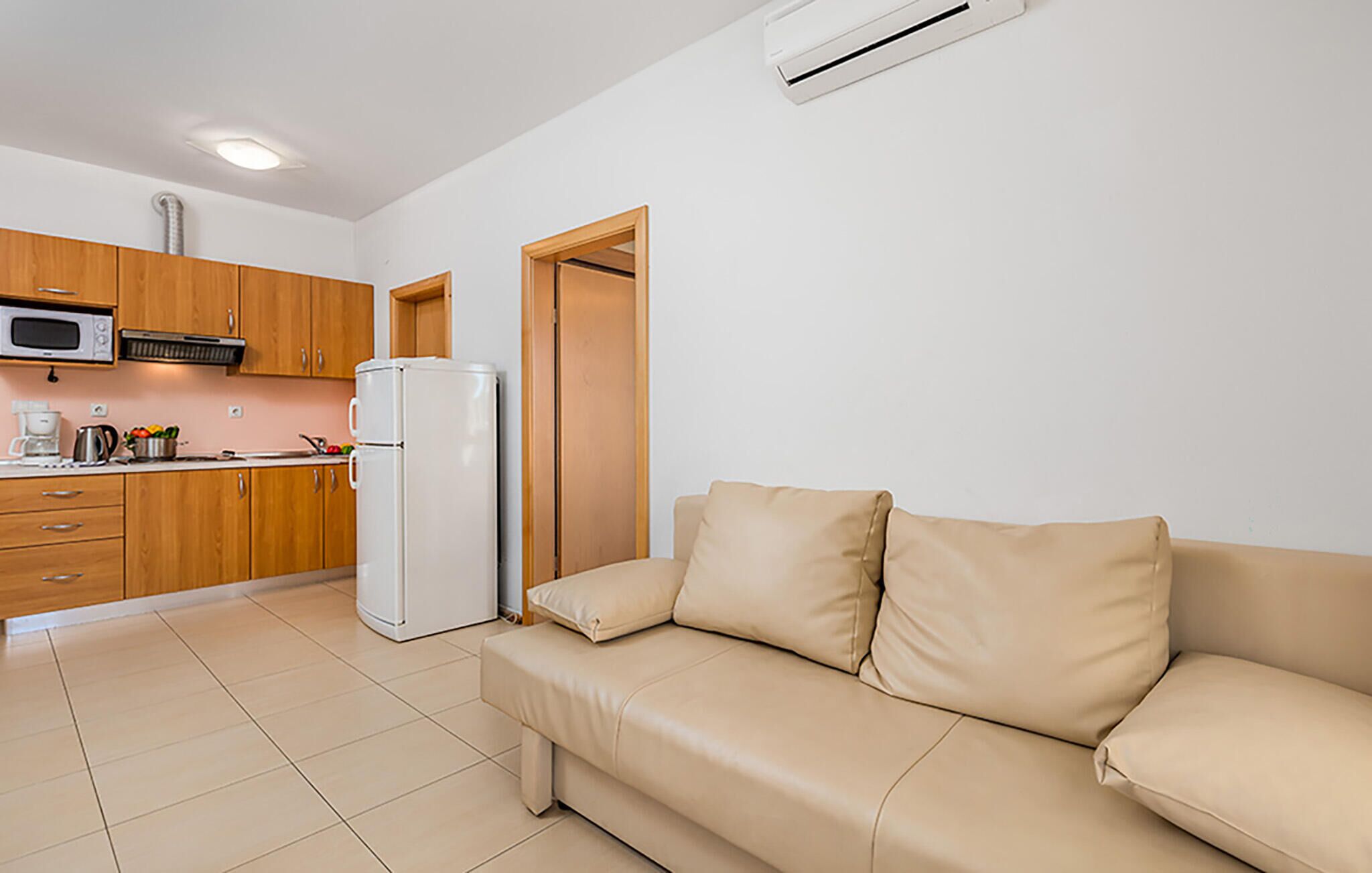 A compact living space with a kitchenette, a beige sofa, and a microwave.