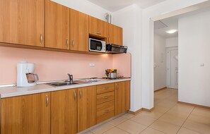 A kitchen with wooden cabinets, a microwave, a coffee maker, and a sink. - Cozy apartment in Palit with WiFi (Palit)