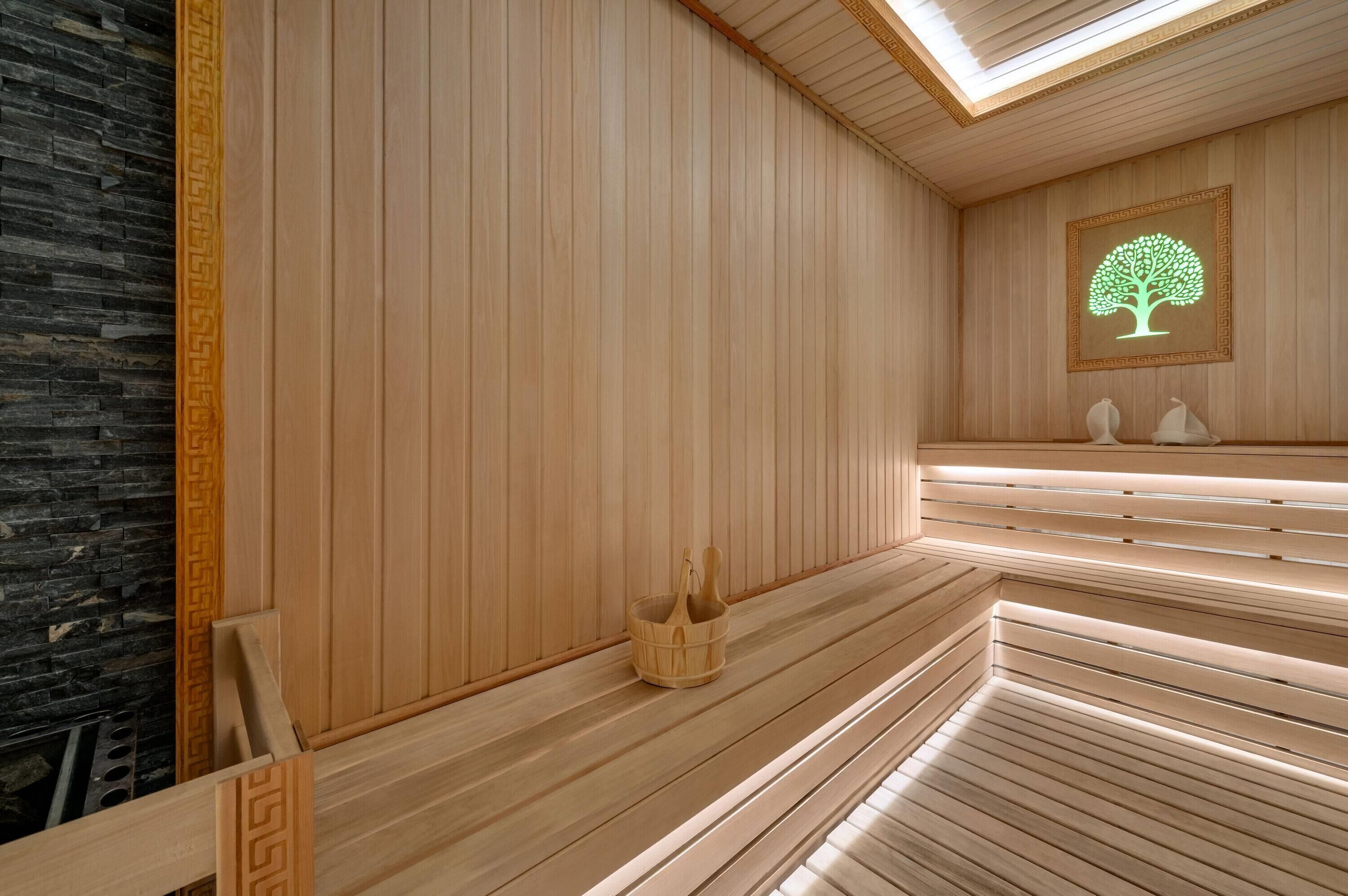 Una sauna con bancos de madera, una pared de piedra y un árbol enmarcado en la pared.