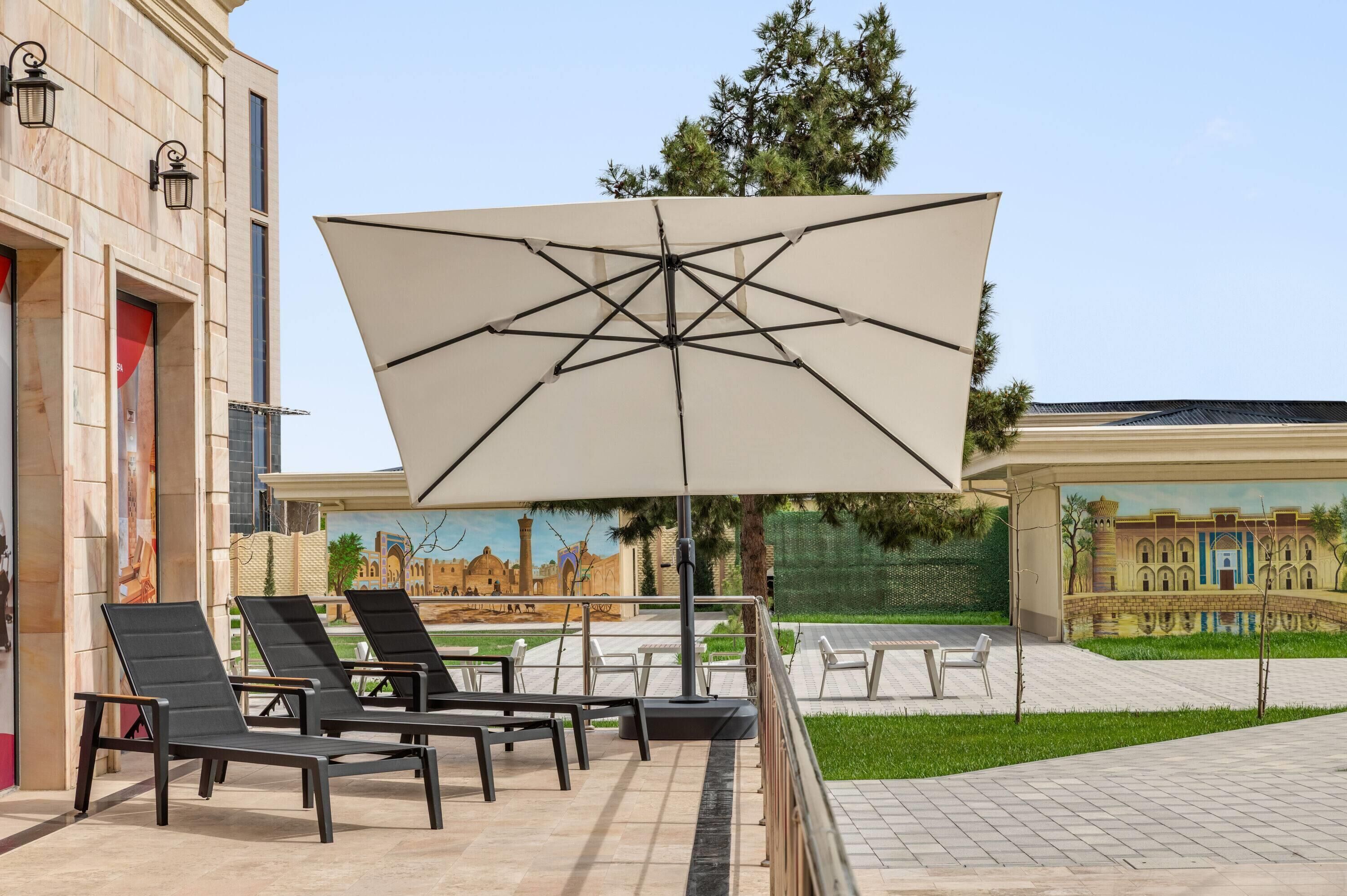 Outdoor seating with umbrellas, a mural, and a building facade.