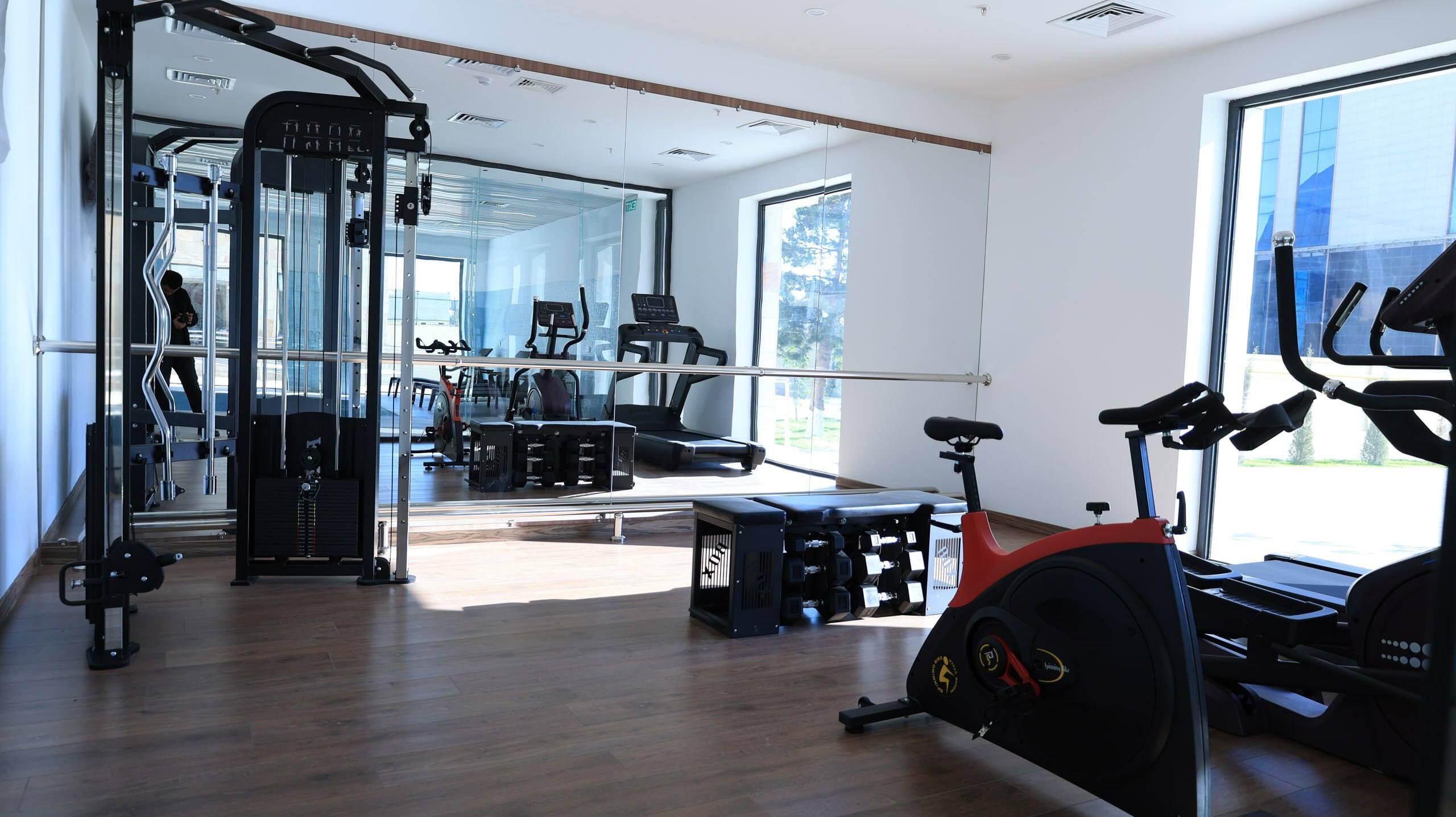 Una palestra moderna con attrezzature cardio, macchinari per pesi e uno specchio a parete.