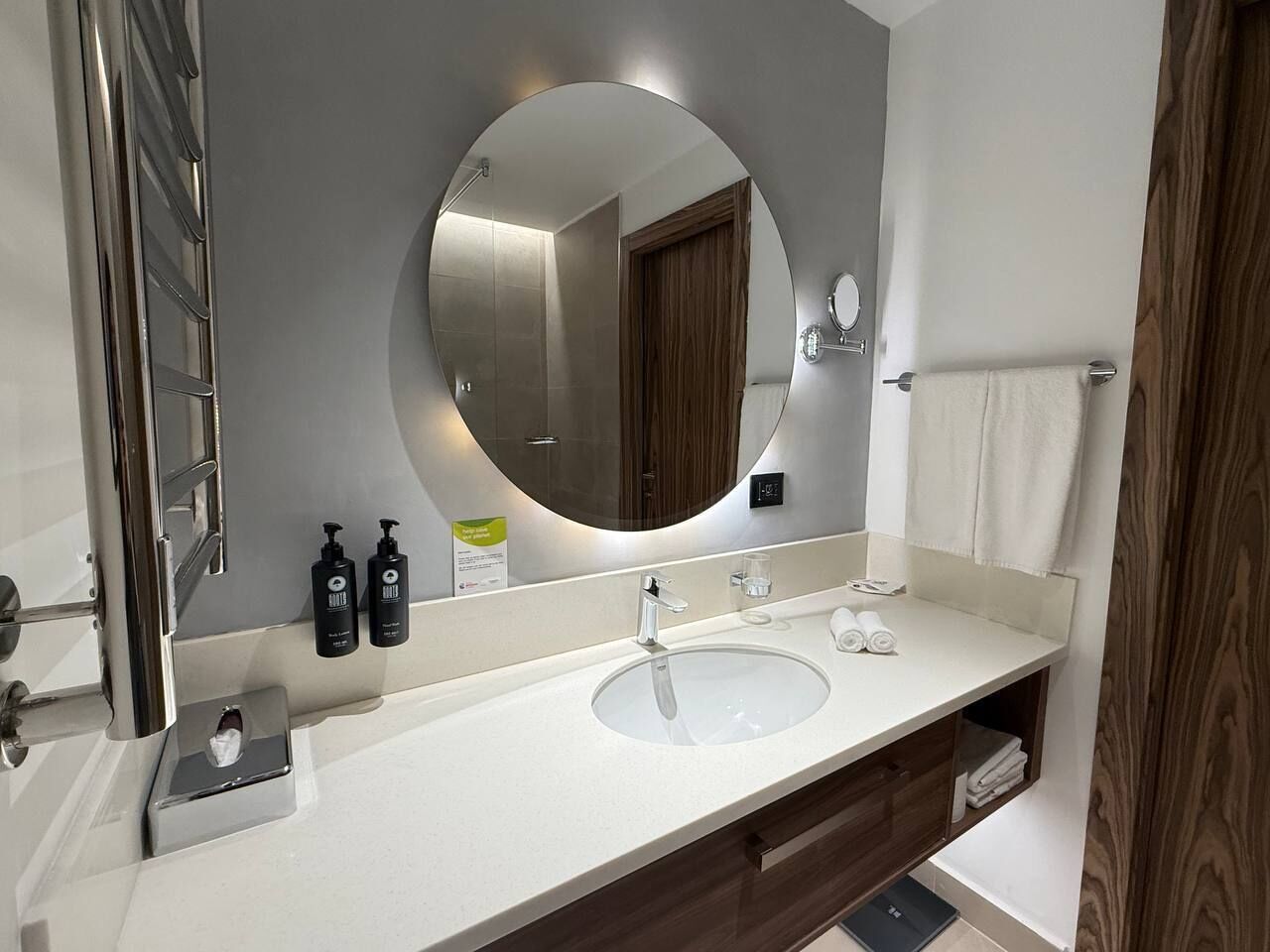 Un baño moderno con un espejo grande, un lavabo y un perchero para toallas.