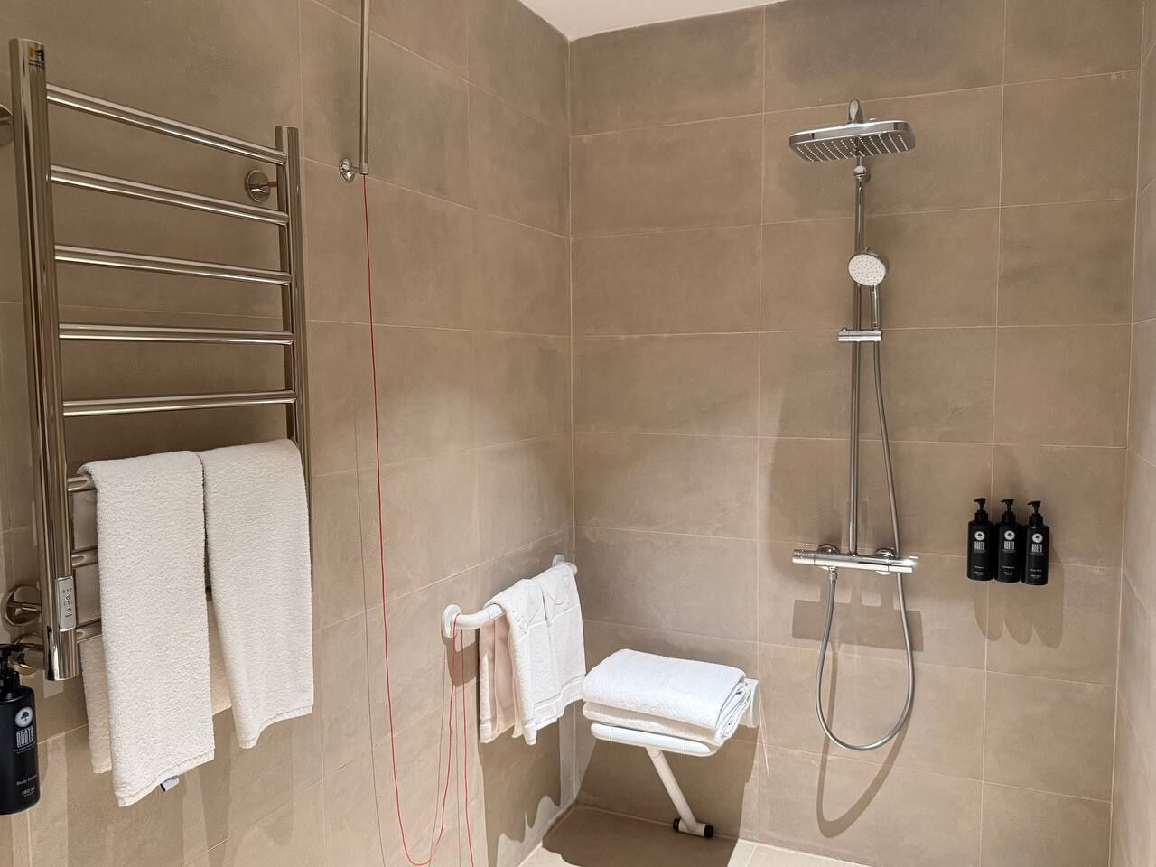 Une salle de bain moderne avec une douche à parois de verre, un porte-serviettes et un petit coin salon.