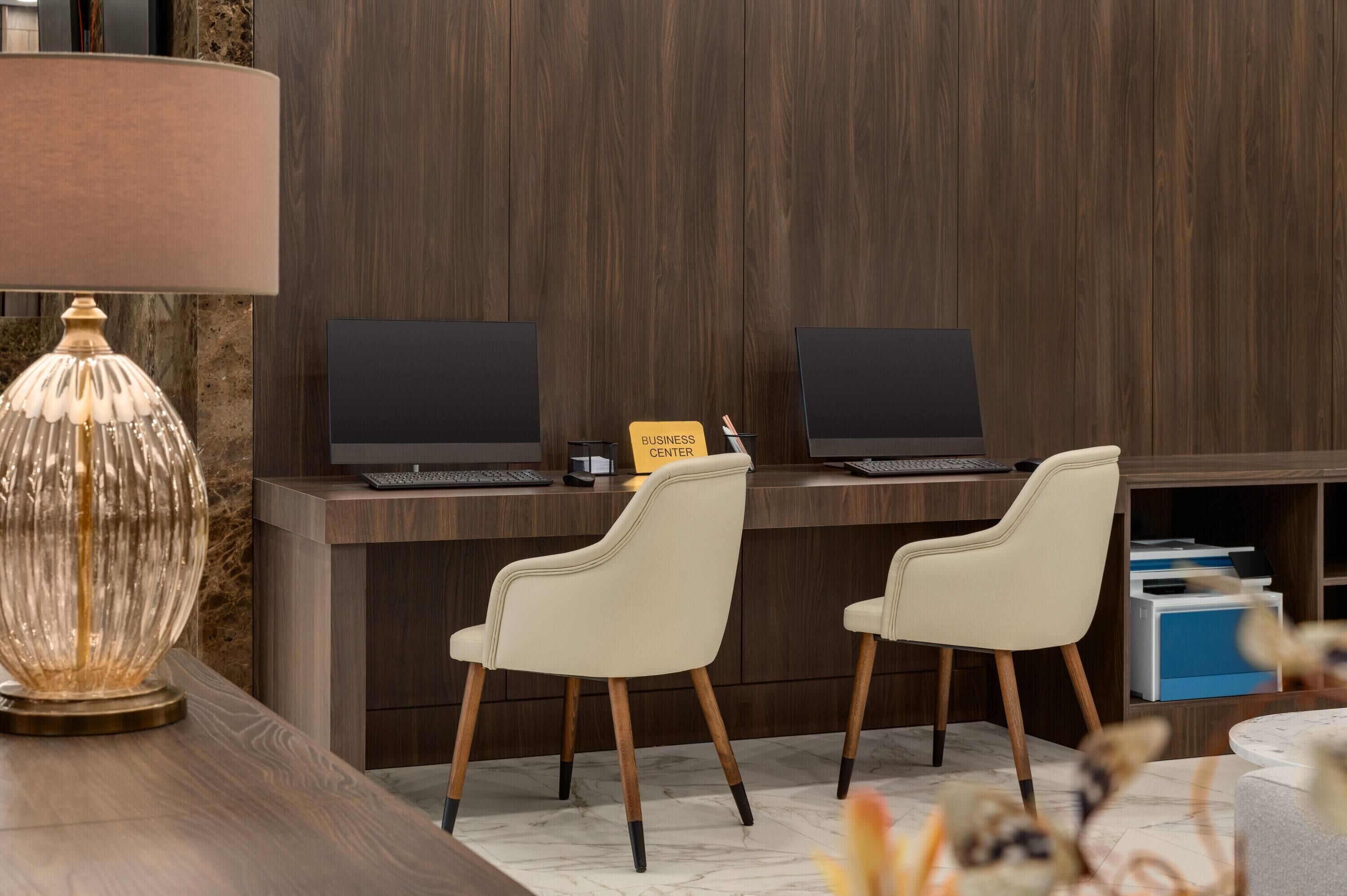 A reception desk with two computers, a sign reading "BUSINESS CENTER," and two white chairs.