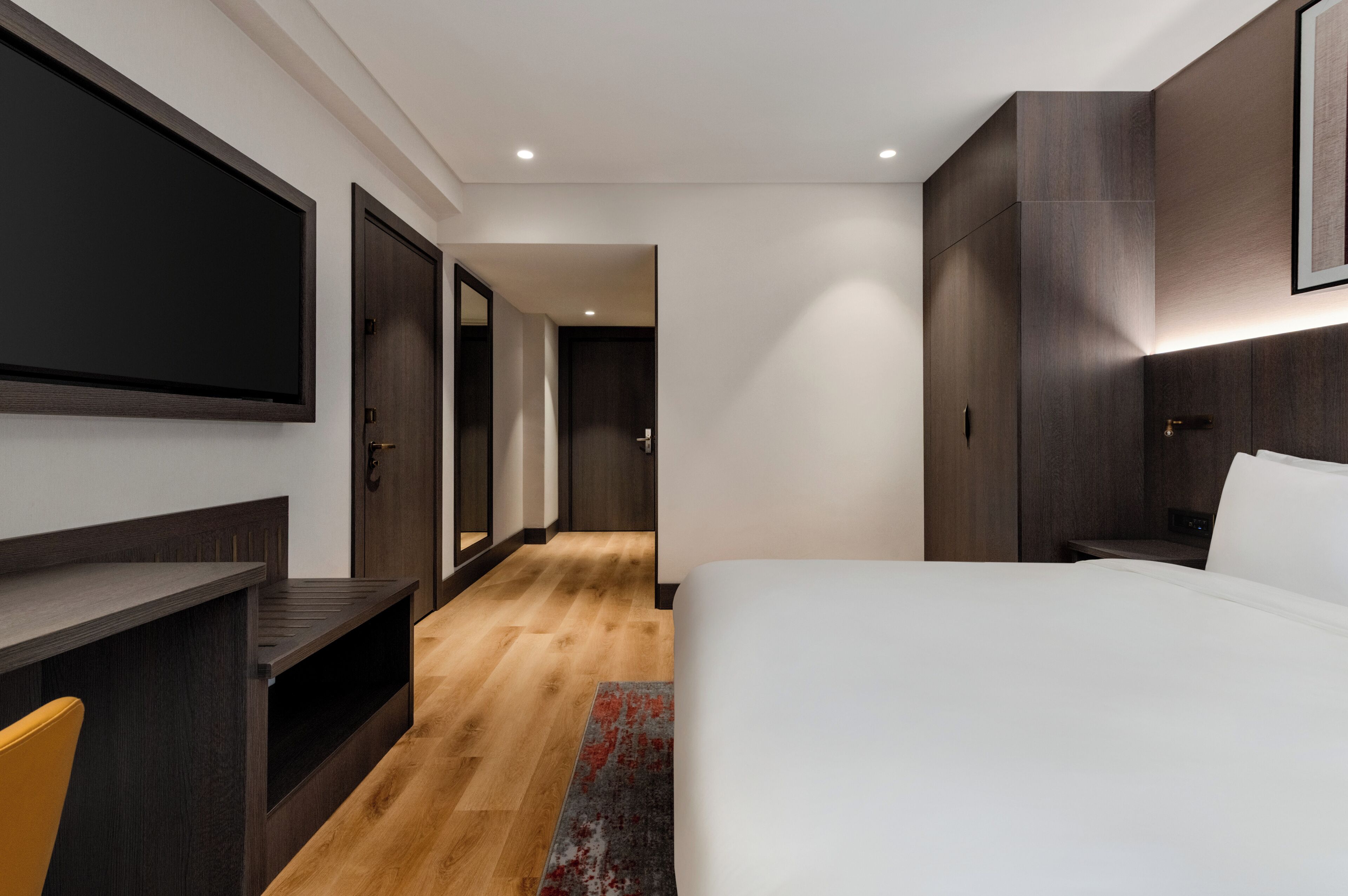 Une chambre d’hôtel moderne équipée d’un grand lit, d’un bureau, d’une télévision et d’une armoire.