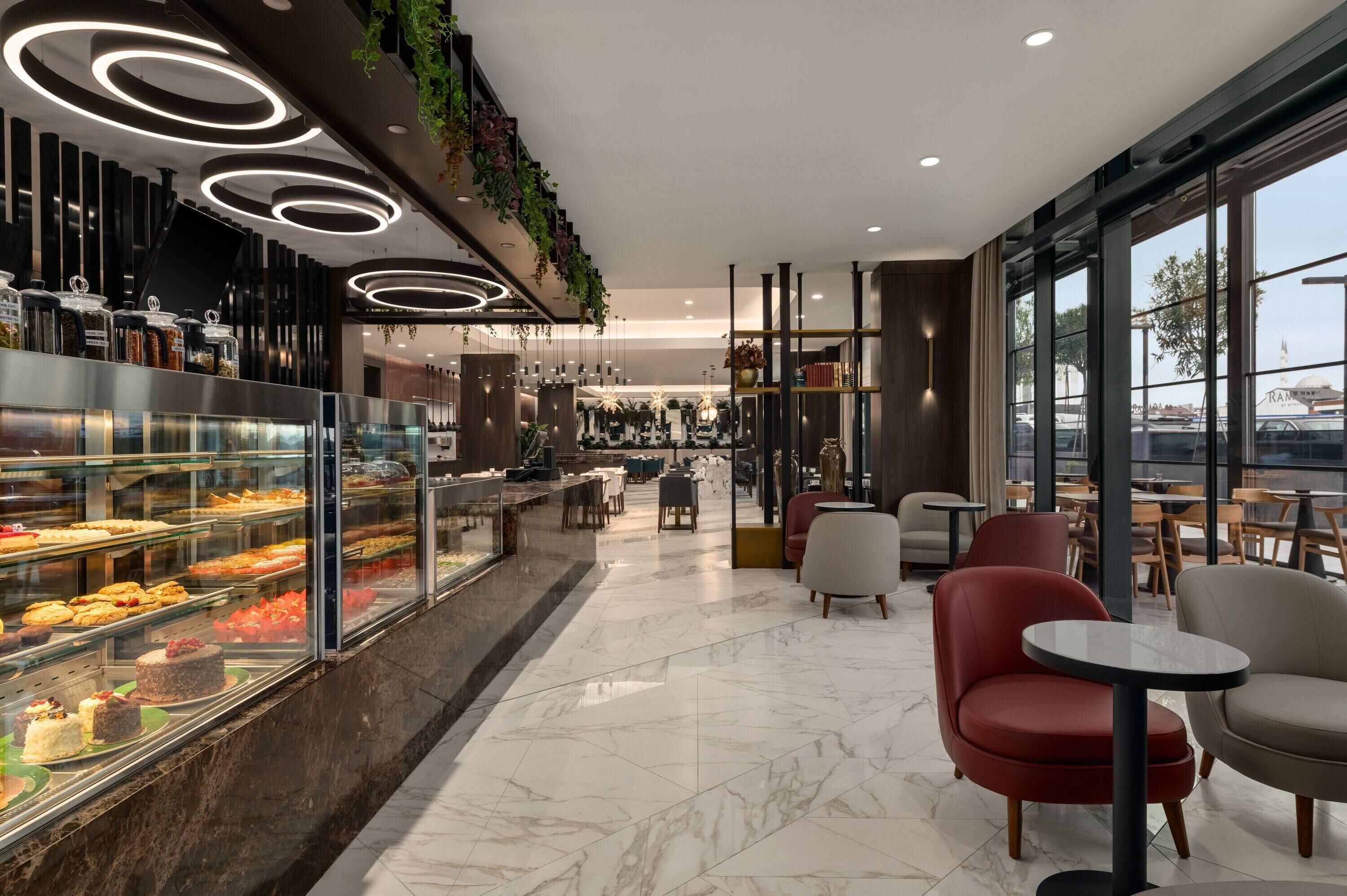 A modern cafe with a glass display case of pastries, comfortable seating, and a view of the street.