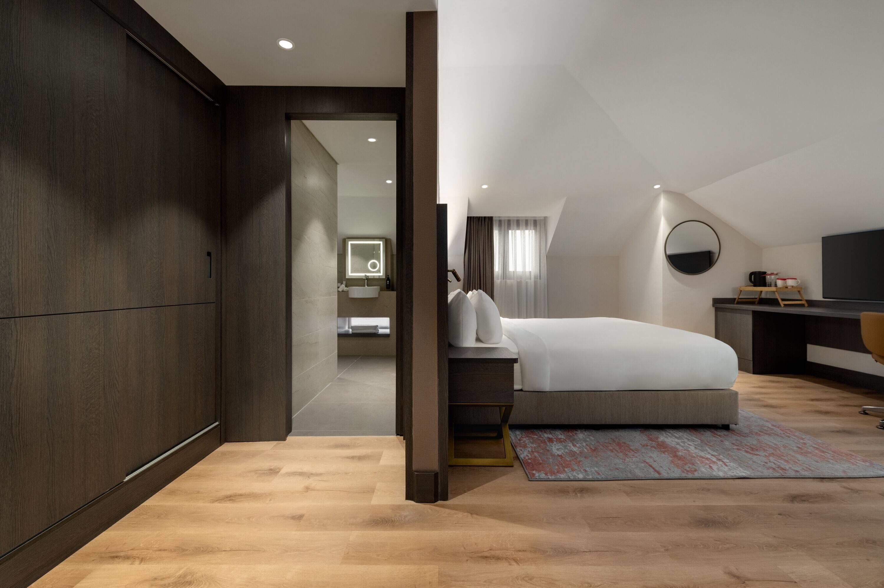 Une chambre à coucher moderne avec un grand lit, un bureau et un miroir.