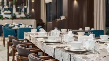 A restaurant with a long marble counter, blue upholstered chairs, and white table settings.