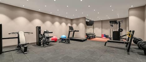 A gym with various exercise equipment including treadmills, weight machines, and free weights.