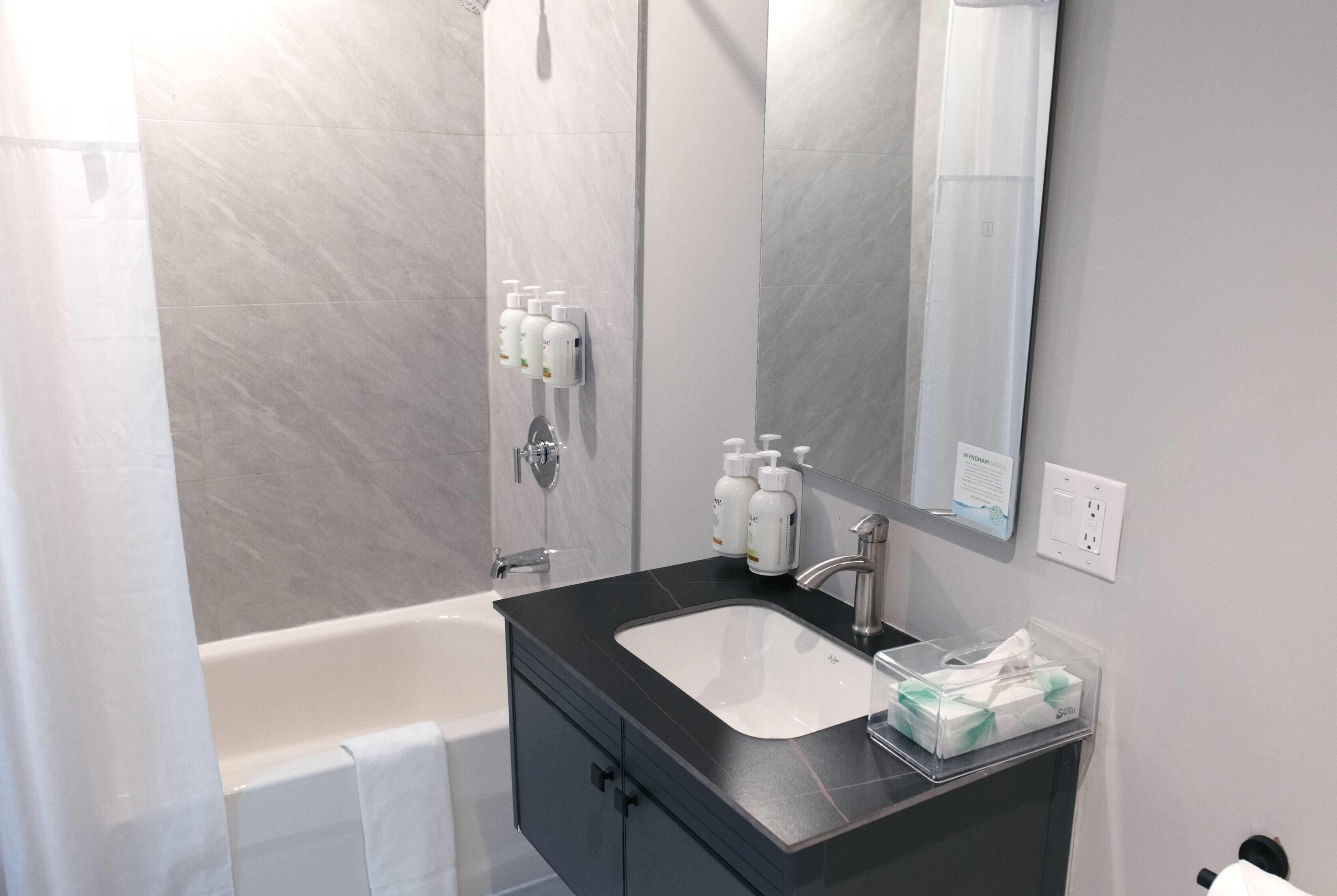 A modern bathroom with a black sink, mirror, and toiletries.