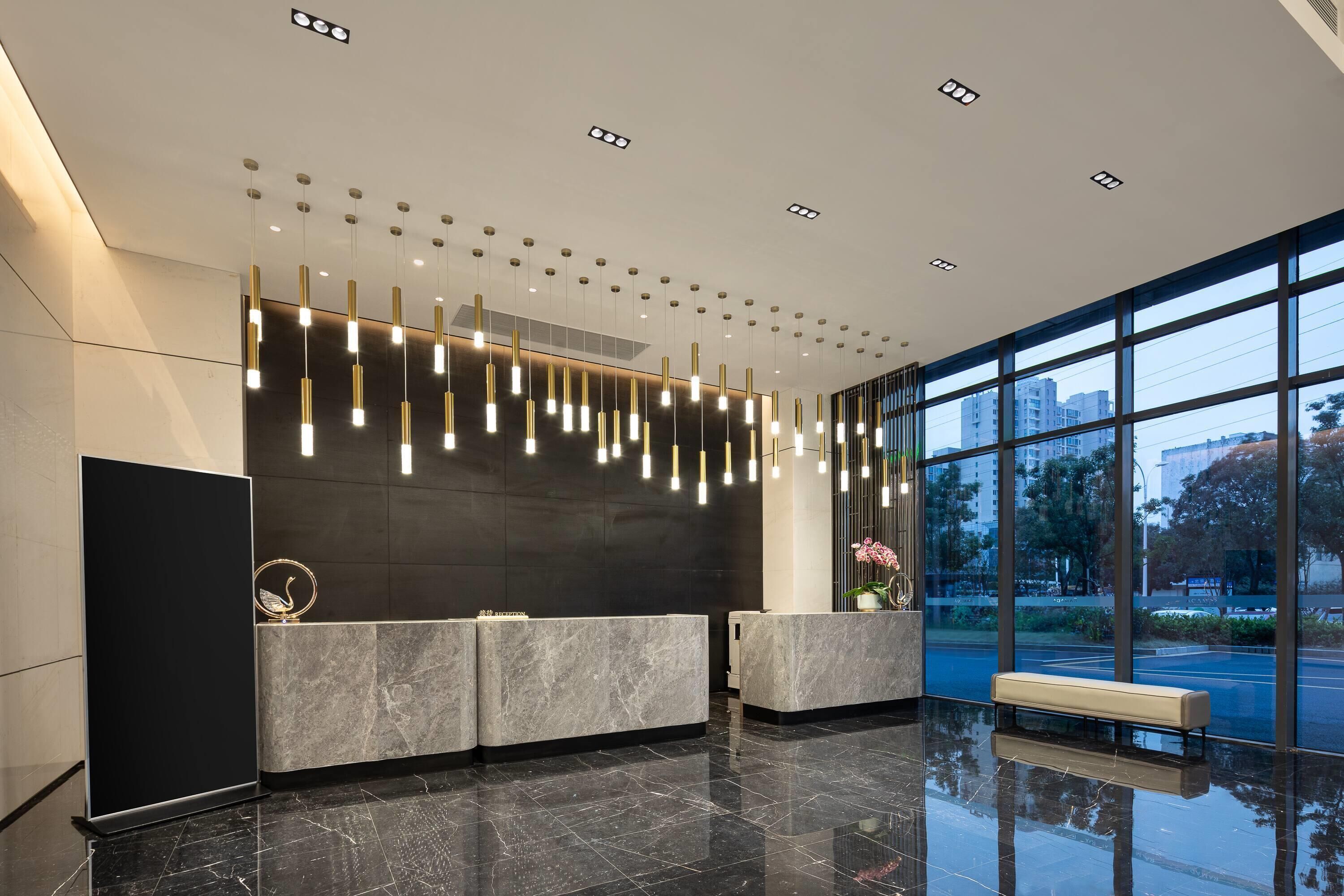 A modern reception area with marble counters, pendant lighting, and a bench.