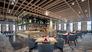 Un restaurant spacieux doté d’un bar central, de plusieurs options d’aménagement pour les places assises et d’un design moderne au niveau du plafond.