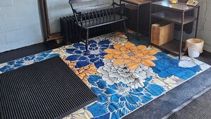 A room with a patterned rug, a bench, a table with a lamp, and a window with curtains. - Smitty's Cozy Corner in Smethport, PA. Spaciously 4-bedroom home (Smethport)