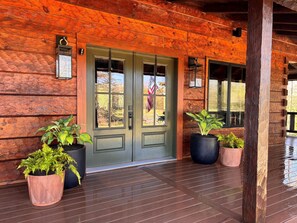 A wooden cabin with a green door, potted plants, and a wooden deck. - Massanutten, Parkway, JMU and Vineyards Galore- sleeps 12 (Elkton)