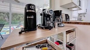 Ett kök med en kaffebryggare, en mixer och en kaffekvarn på en bänkskiva i trä.