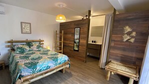 Une chambre à coucher avec un lit, une échelle en bois, un banc en bois et une salle de bain avec un miroir et un lavabo.