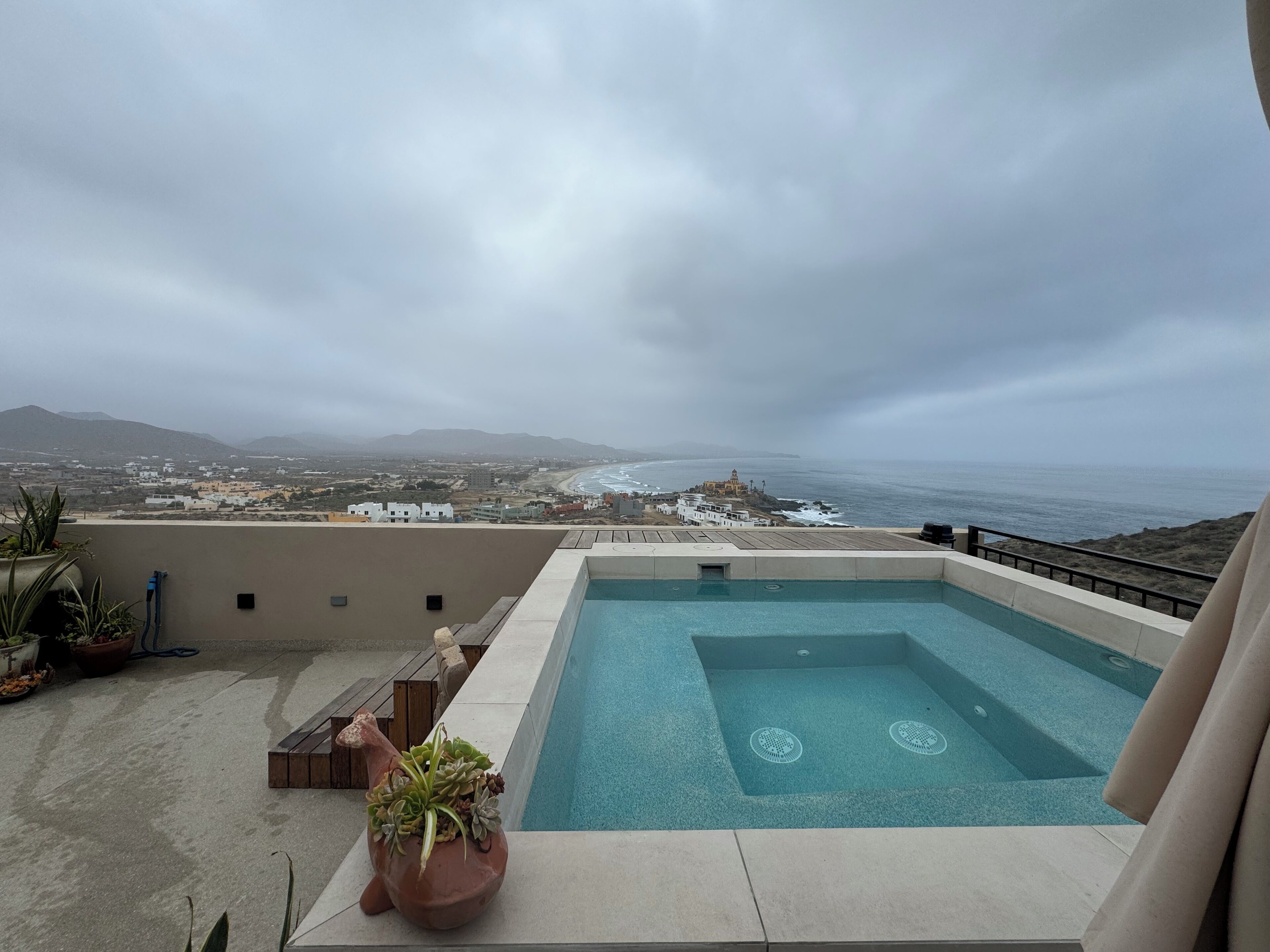 A rooftop pool with a view of the ocean and distant mountains.